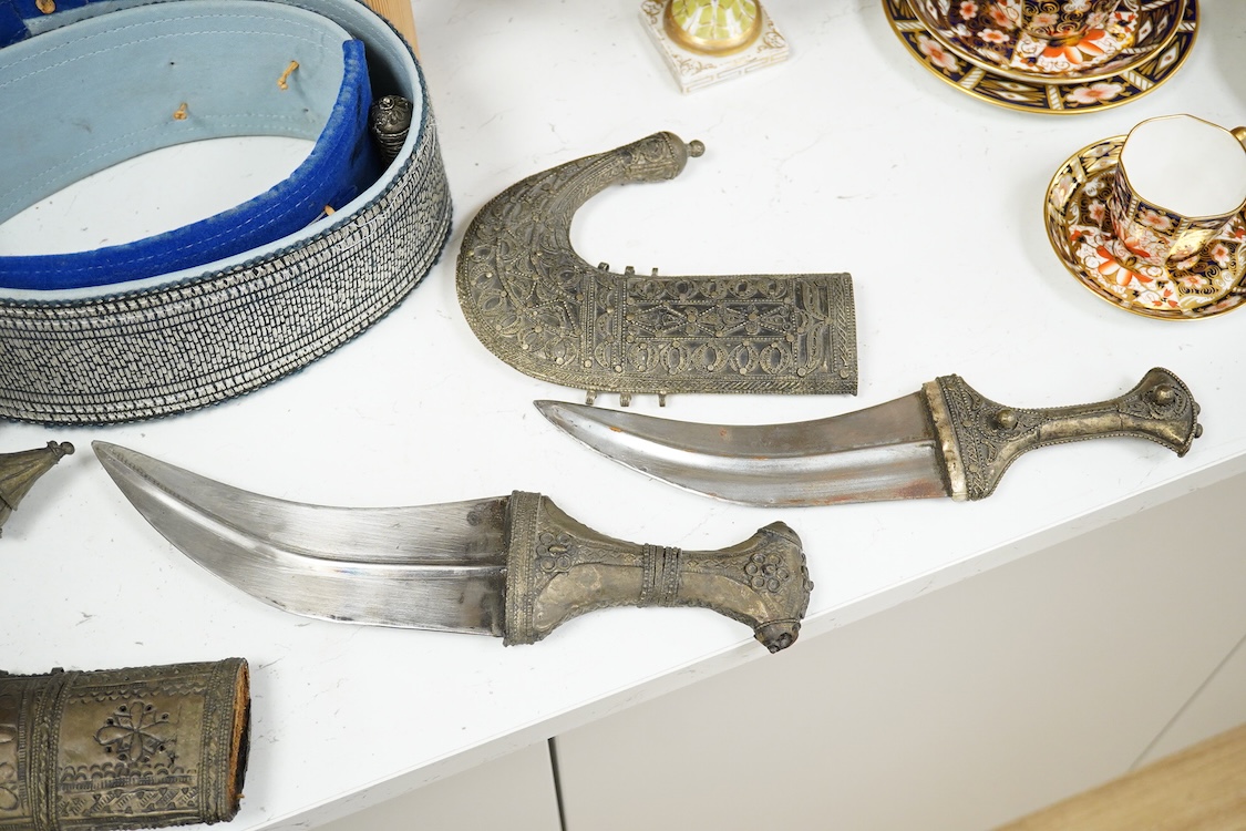 Two Yemeni white metal daggers white and two belts, largest dagger 31cm long